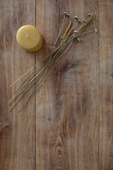 Top down view of a yellow candle and dried field flowers on a oak wood surface with copy space.