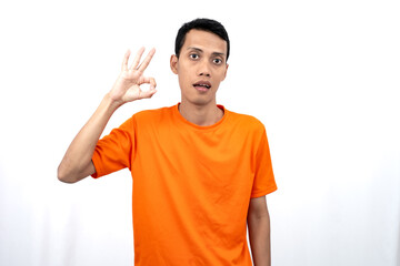 Portrait of a young Asian man wearing an orange t-shirt giving a thumbs up, okay, agree sign....