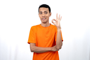 Portrait of a young Asian man wearing an orange t-shirt giving a thumbs up, okay, agree sign....