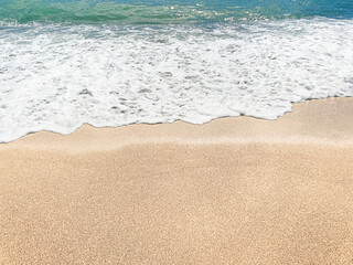 A sea wave on flat sand. Sand and sea. Beach. Summer, natural background. The seashore. View from above. Close-up. Copy space