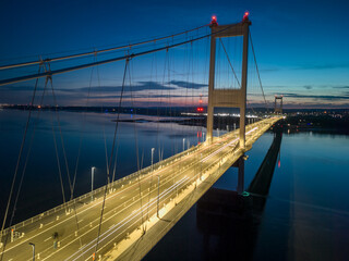Obraz premium Suspension bridge connecting cities with illuminated road at twilight