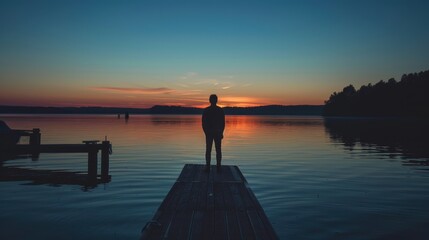 Fototapeta premium Tranquil Evening Silhouette: Person Standing on Dock at Dusk