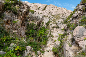 Narrow, rocky gorge Vrzenica (Žig Vrženica) cuts through rugged landscape in Baska, Krk Otok, Primorje-Gorski Kotar, Croatia. Scenic hiking trail through dramatic canyon leading to Vela and Mala Luka