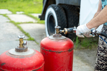 Gas cylinder filling process. A person's hands connect the gas supply hose.