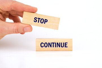 Conceptual symbol. Copy space. Stop or continue words written phrase made of wooden blocks is laid out on a white background