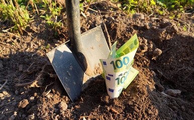 Shovel with Euro money on ground. Bury money. Digging money in soil. Digs EURO coins note from...