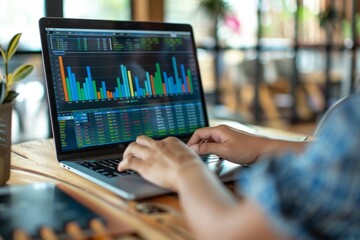 Hands typing financial data on laptop