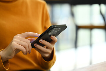 Young stylish woman typing text message on mobile phone, sitting at coffee shop