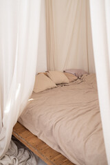 Bright Scandi style interior in the bedroom. A canopy, a linen bed and a jute rug. Full-height windows. High quality photo.