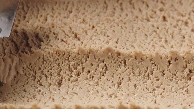 Slow motion closeup hazelnut praline ice cream scooping
