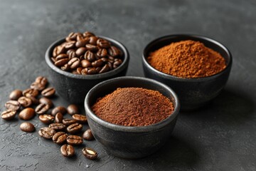 Different forms of coffee: whole beans, ground coffee, and instant coffee, presented in black ceramic bowls on a dark background.