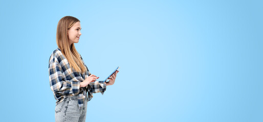 Woman smiling and using a tablet in casual attire on a blue back