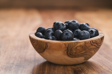 Fresh blueberries in wood bowl on table slightly toned