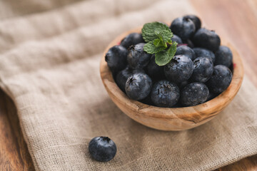 Fresh blueberries in wood bowl on table with napkin slightly toned