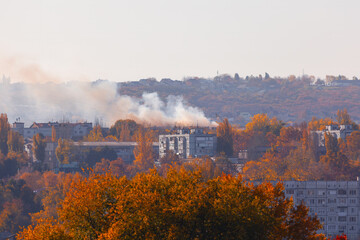 City with smoke in the air and trees in the background in the autumn. Fire in the city
