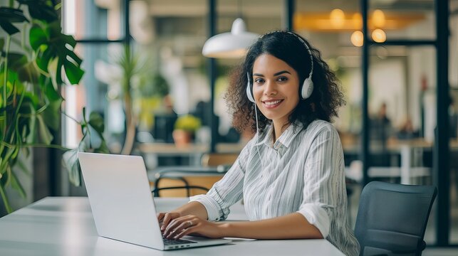 Smiling customer service representative efficiently managing client queries on laptop in modern office environment, highlighting professionalism and effective communication skills