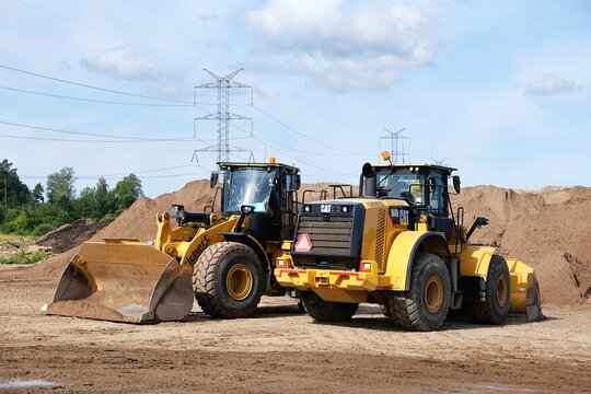 Bakowo, Poland - 3 August 2024: Two yellow bulldozers CAT are standing on a construction site next to a pile of earth