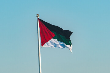 Symbol of Jordanian Pride. Jordan’s Flag Waves Proudly Against Clear Blue Sky