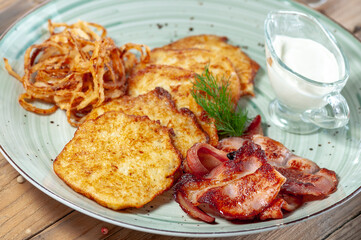 Ukrainian national dish Deruna from potatoes in a plate with sour cream and greens macro photo