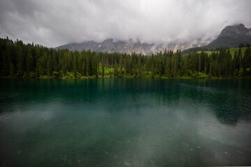 Serene Reflection of Pine Forest and Mountains Beneath Dramatic Cloudy Sky at Dusky Twilight