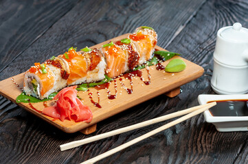 sushi set philadelphia with salmon on a wooden board on a dark background with a sauce pan