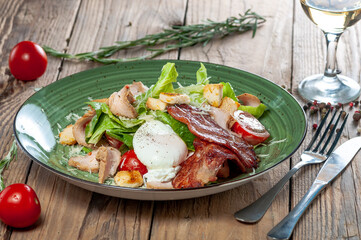 caesar salad in the author's presentation on a green plate on a wooden background
