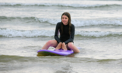 Beautiful smiling young girl surfing the waves in summer.