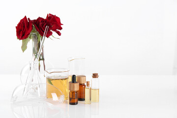 Aromatherapy product. Glassware with essential oils and roses on white table in laboratory, space for text