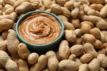 Tasty peanut butter in bowl among groundnuts