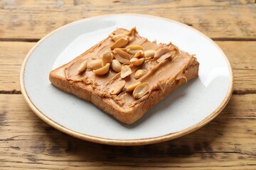 Delicious sandwich with peanut butter and fresh nuts on wooden table, closeup