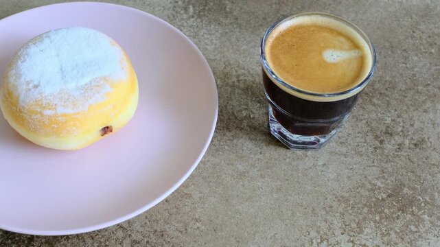 Close-up of berliner cake on a white plate and a cup of espresso
