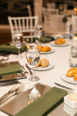 A stunning wedding reception table with white linens, gold accents, and lush greenery. The table is set with elegant glassware and silverware, perfect for weddings, parties, and other special events