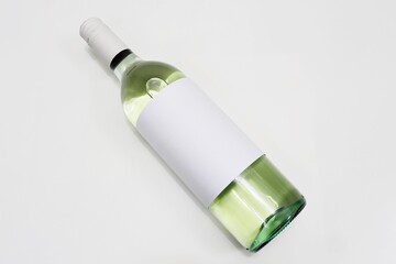 Bottle of white wine laying down, empty label, isolated white background