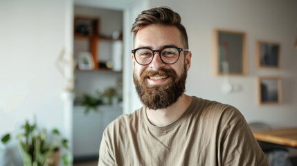 Naklejka premium A bearded man in a casual setting smiles warmly, radiating positivity and a welcoming aura in a cozy indoor environment.