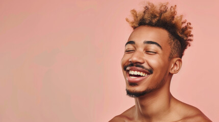 A young man with light brown curly hair beams with joy against a peach-toned background, capturing a moment of pure happiness.