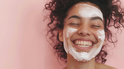 A woman with curly hair and a radiant smile indulges in a skincare routine, her face adorned with a creamy facial mask, generating a feeling of self-care and bliss.