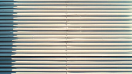 A minimalist abstract image of a white metal shutter casting intricate shadows in the evening light.
