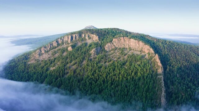 Famous Aigir rocks at Ural mountains in foggy morning. Scenery rocky cliff on a mountain covered by forest. 4k Aerial drone footage