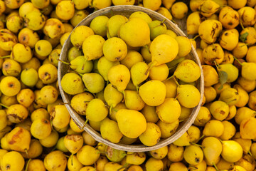 Yellow pears in a basket on the counter of a farmers market.