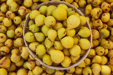 Yellow pears in a basket on the counter of a farmers market.