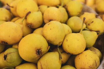 Yellow pears in a basket on the counter of a farmers market.