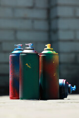 Many spray paint cans outdoors on sunny day
