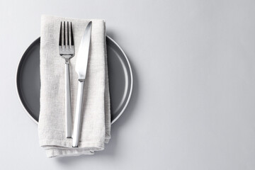 Stylish silver cutlery, plate and napkin on white background, top view. Space for text