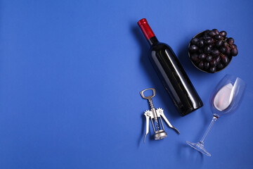 Wing corkscrew, wine, grapes and glass on blue background, flat lay. Space for text
