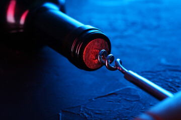 Wine bottle with corkscrew in lights on table, closeup