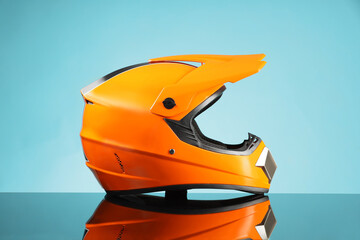 Modern motorcycle helmet with visor on mirror surface against light blue background