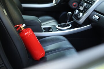 Red fire extinguisher in automobile. Car safety equipment