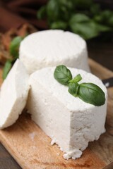 Fresh ricotta (cream cheese) and basil on wooden table, closeup