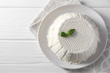 Tasty ricotta (cream cheese) and basil on white wooden table, top view. Space for text