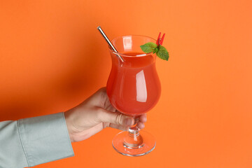 Woman with glass of refreshing cocktail on orange background, closeup